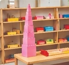 Montessori shelves with a pink tower and learning materials