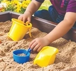 Hands playing with buckets and spades in a sandpit